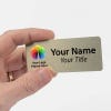 A hand holding a 1.5 x 3.5 Gold Name Tag