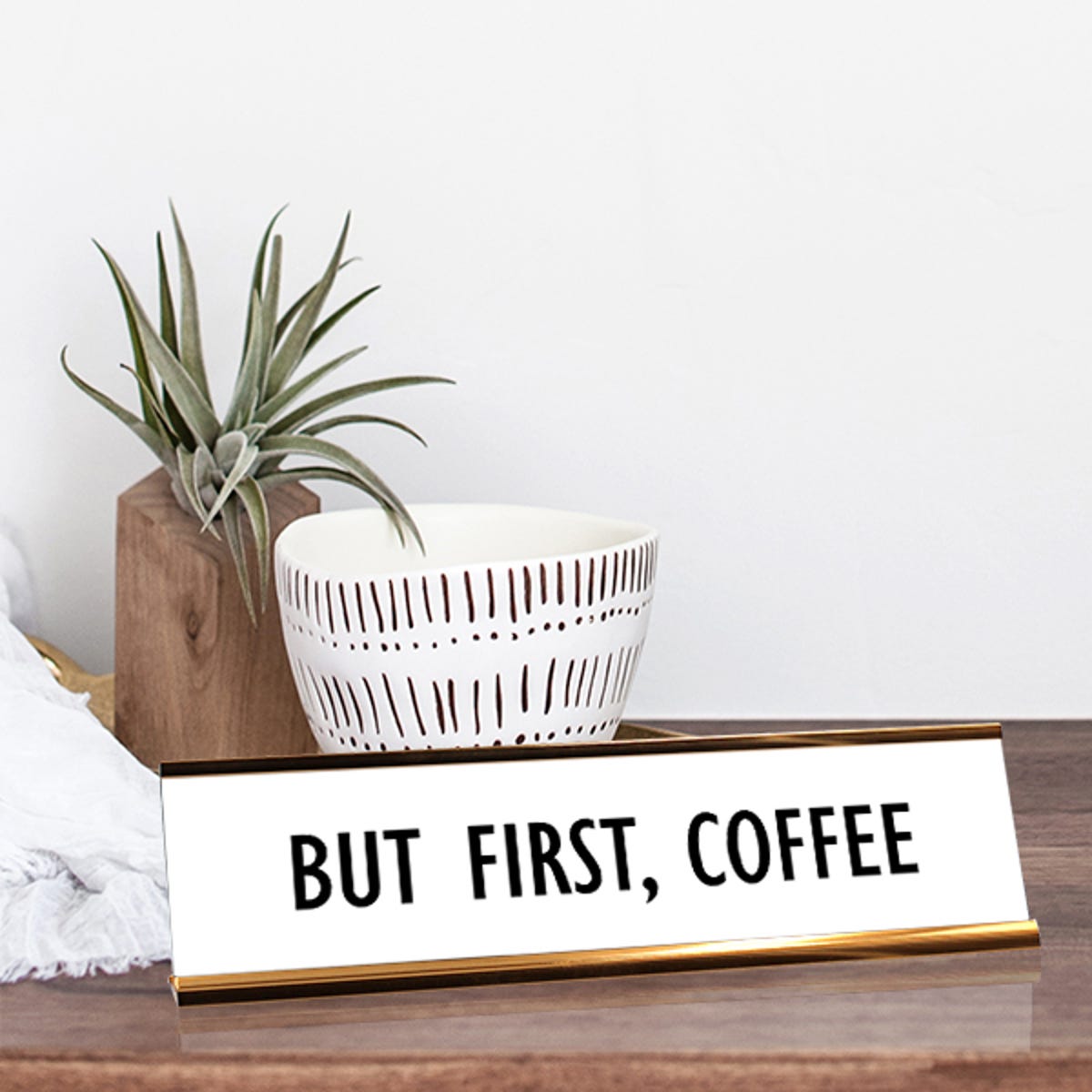 White desk plate with black custom text in yellow gold holder on a desk