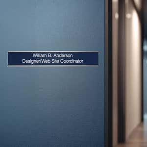 A blue name plate with a silver aluminum wall holder on an office door