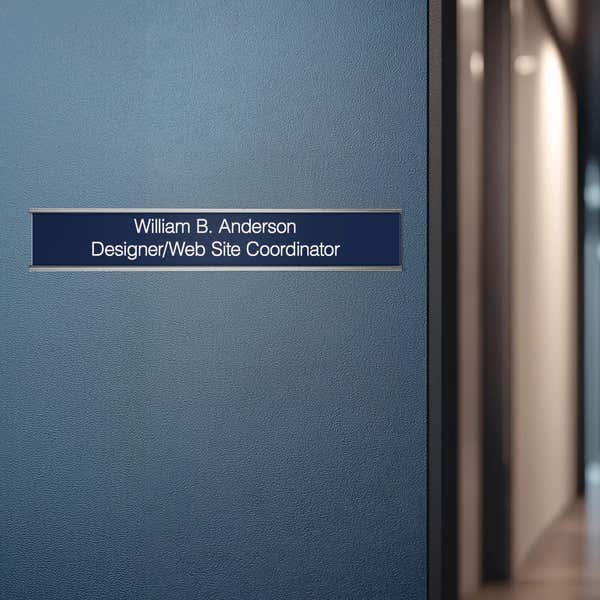 A blue name plate with a silver aluminum wall holder on an office door