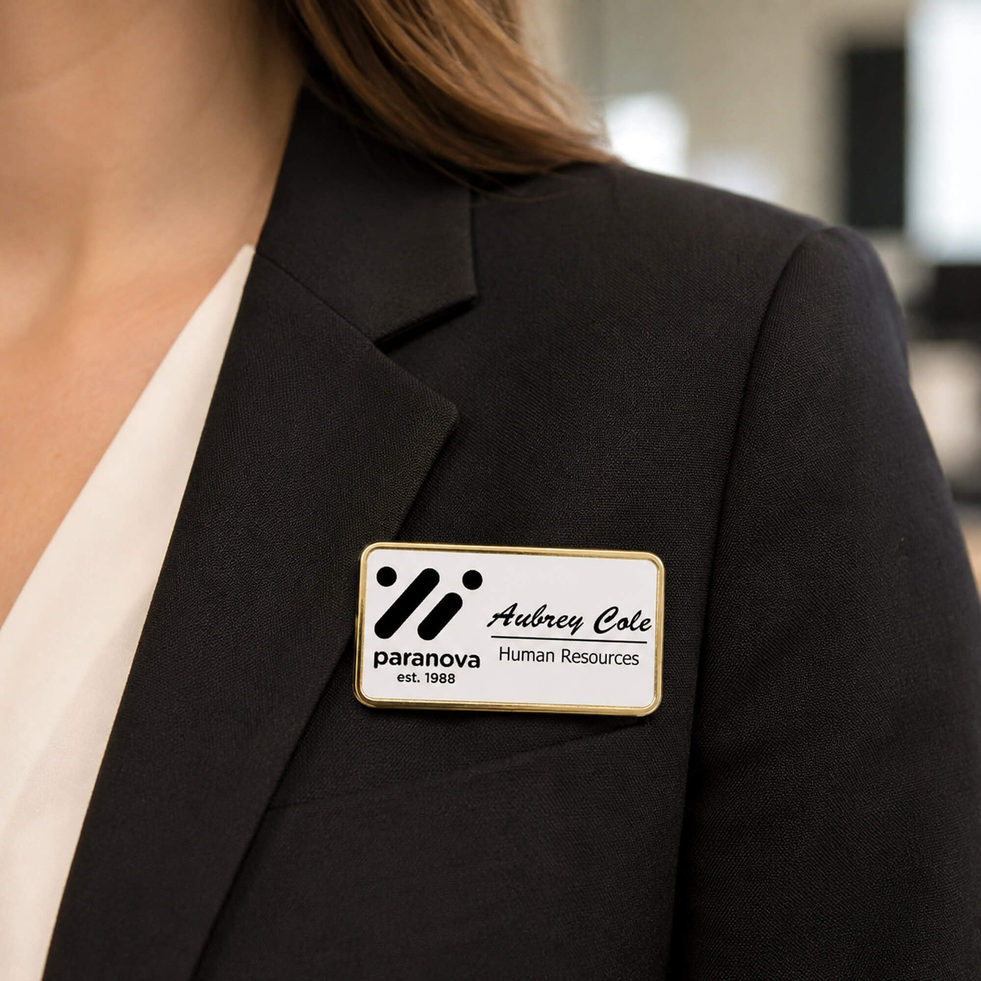 1.5x3 executive engraved name badge with gold beveled frame worn on black blazer — professional name tag with logo for corporate employees