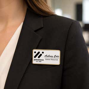 1.5x3 executive engraved name badge with gold beveled frame worn on black blazer — professional name tag with logo for corporate employees