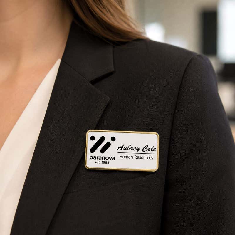 1.5x3 executive engraved name badge with gold beveled frame worn on black blazer — professional name tag with logo for corporate employees