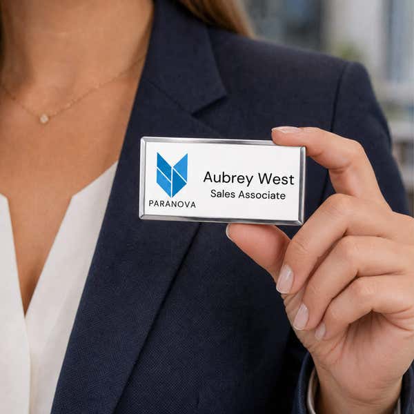 Full color custom name badge with silver frame held by professional — personalized name tag